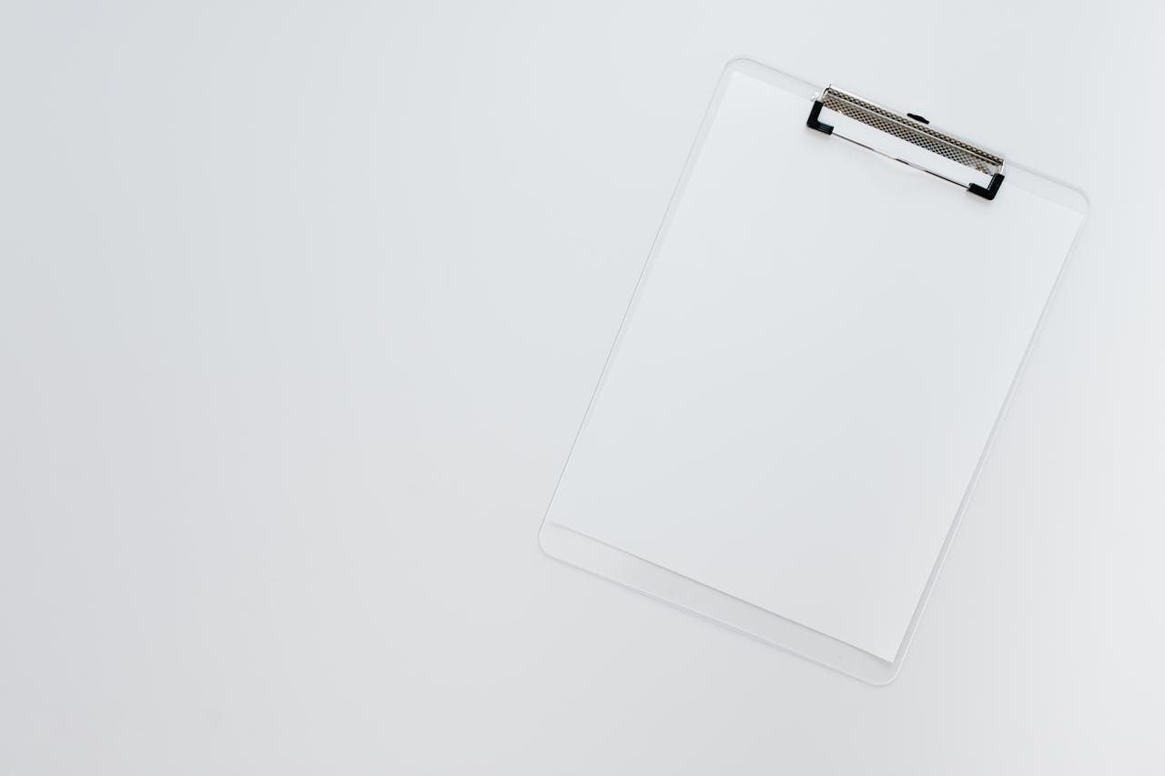 Minimalist top view of a transparent clipboard on a white background offering ample copy space.